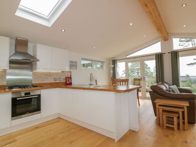 A kitchen with wooden countertops and white cabinets opening to a living area with a brown sofa and wooden nesting tables at 11 Faraway Fields in Dobwalls