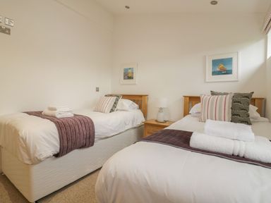 A bedroom with two single beds with pillows and towels and a bedside table with a lamp at 11 Faraway Fields in Dobwalls
