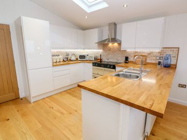 A kitchen with white cabinets wooden countertops and a stainless steel sink at 12 Faraway Fields in Dobwalls