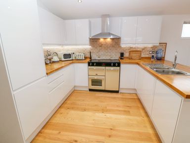 A kitchen with white cabinets wooden countertops a stove a microwave kettle toaster and a sink at 12 Faraway Fields in Dobwalls