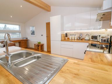 A kitchen with wooden countertops a double sink and white cabinets at 12 Faraway Fields in Dobwalls