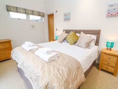 A bedroom with a bed with pillows and folded towels on it bedside tables with lamps and a wooden dresser at 12 Faraway Fields in Dobwalls