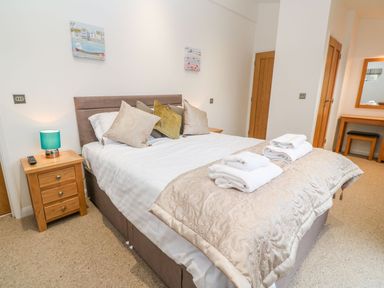 A bedroom with a double bed pillows and towels bedside tables and a dressing table with a mirror at 12 Faraway Fields Dobwalls
