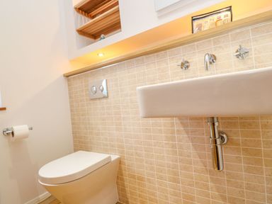 A bathroom with a wall-mounted toilet and sink with tiled wall at 12 Faraway Fields in Dobwalls