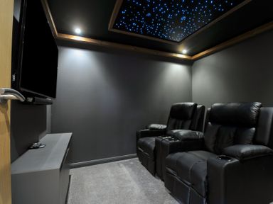 A home theater with black recliner chairs and a television at 24 Meadow Retreat Dobwalls