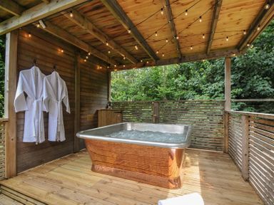 An outdoor spa area with a hot tub and robes at 24 Meadow Retreat in Dobwalls
