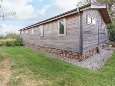 An exterior view of a wooden house with stone foundation and grass lawn at 15 Faraway Fields in Dobwalls