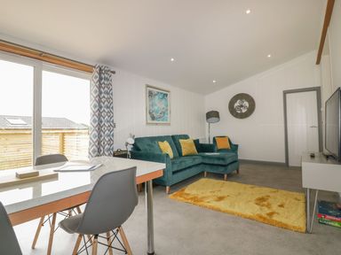A living room with a green sofa yellow rug dining table and chairs at 18 Meadow Retreat in Dobwalls