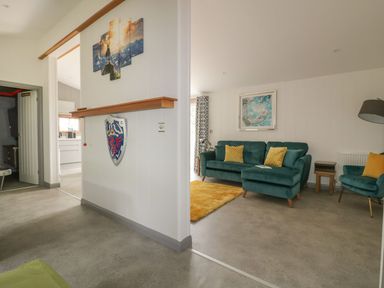 A living room with teal sofa yellow pillows and a yellow rug at 18 Meadow Retreat in Dobwalls