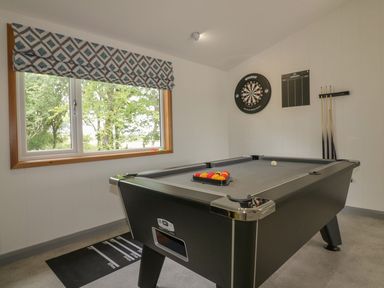 A game room with a pool table, a dartboard, and a window with a patterned curtain at 18 Meadow Retreat in Dobwalls