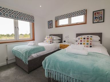 A bedroom with two single beds white bedding teal throws and polka dot pillows at 18 Meadow Retreat in Dobwalls