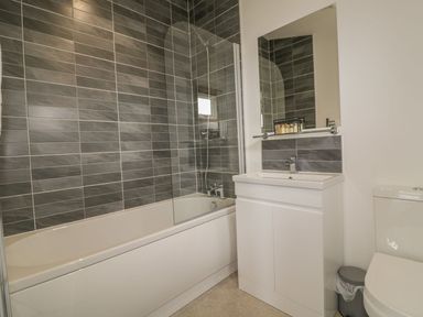 A bathroom with a bathtub shower combo white sink cabinet mirror and toilet at 18 Meadow Retreat in Dobwalls