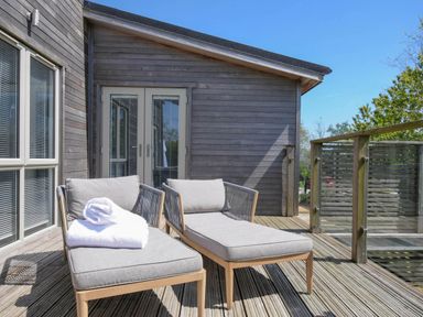 A deck with two lounge chairs and a towel outside a wooden house at 11 Meadow Retreat in Dobwalls