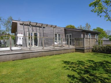 An outdoor view of a wooden house with a deck chairs and robes hanging on the wall at 11 Meadow Retreat in Dobwalls