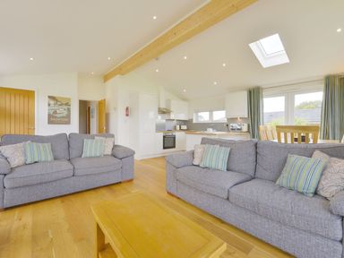 A living room with two gray sofas a wooden coffee table an open kitchen with white cabinets and a dining area at 4 Horizon View in Dobwalls