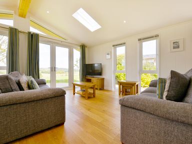 A living room with two grey sofas a wooden coffee table a television and large windows at 4 Horizon View in Dobwalls