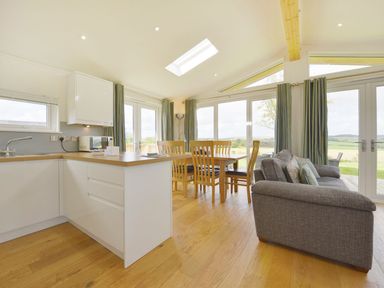 An open kitchen and dining area with wooden dining table and chairs and a grey sofa at 4 Horizon View in Dobwalls