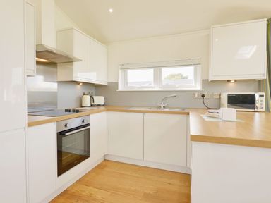 A kitchen with white cabinets wooden countertops a built in oven a toaster a kettle a microwave and a window at 4 Horizon View in Dobwalls