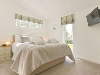 A bedroom with a bed a side table a window mounted television and windows at 4 Horizon View Dobwalls