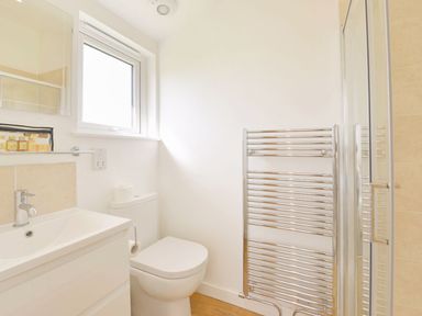A bathroom with a sink, toilet, window, towel heater, and shower at 4 Horizon View in Dobwalls