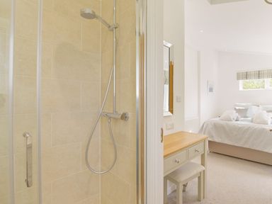 A bathroom shower area with beige tiles next to a bedroom with a bed desk and mirror at 4 Horizon View in Dobwalls