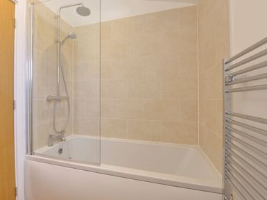 A bathroom with a bathtub shower combination and metal towel rail at 4 Horizon View in Dobwalls