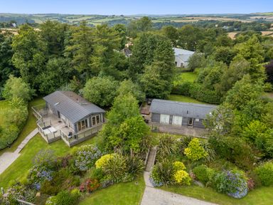 Two wooden houses surrounded by trees and gardens with colorful flowers at 4 Horizon View in Dobwalls