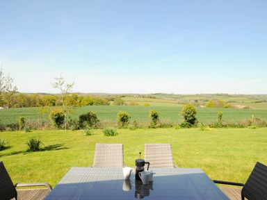 A garden with a table and four chairs overlooking fields and hills at 4 Horizon View in Dobwalls