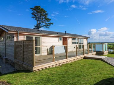 A wooden single-story house with a deck and glass railings overlooking a grassy yard at 14 Faraway Fields in Dobwalls