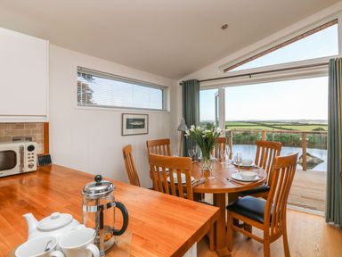 A dining area with a round wooden table set for a meal and wooden chairs with an outdoor view at 14 Faraway Fields in Dobwalls