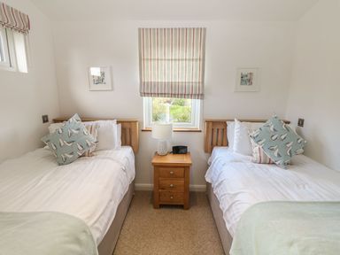 A bedroom with two single beds a wooden nightstand and a window with striped blind at 14 Faraway Fields in Dobwalls