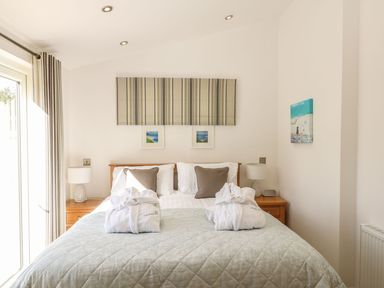 A bedroom with a double bed two bedside tables lamps and framed artwork at 14 Faraway Fields in Dobwalls