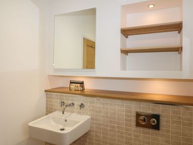 A bathroom with a wall-mounted sink mirror wooden shelves and small toiletries at 14 Faraway Fields in Dobwalls