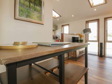 A wooden dining table with items on top near windows with blinds and wooden floor at 9 Meadow Retreat in Dobwalls