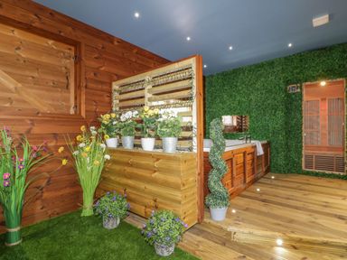 An indoor spa area with a wooden tub surrounded by plants and green wall at 9 Meadow Retreat in Dobwalls
