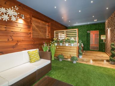 A room with wooden walls and a wicker sofa with white cushions and a yellow pillow at 9 Meadow Retreat in Dobwalls