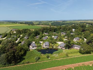An aerial view of bungalows near a pond and fields at 9 Meadow Retreat in Dobwalls