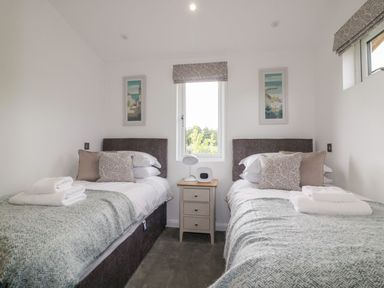 A bedroom with two single beds with pillows and folded towels a nightstand with a lamp and clock and artwork on the walls at 7 Meadow Retreat in Dobwalls