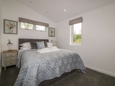 A bedroom with a double bed bedside tables lamps and framed pictures at 7 Meadow Retreat in Dobwalls
