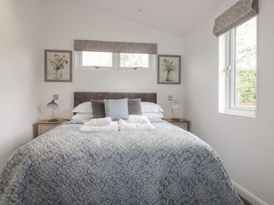 A bedroom with a bed with pillows and folded towels next to a window at 7 Meadow Retreat in Dobwalls