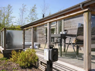 Decking area with table and chairs outside a wooden building at 7 Meadow Retreat in Dobwalls