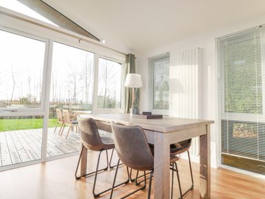 A dining area with a wooden table and chairs near large windows and a glass door at 14 Horizon View in Dobwalls