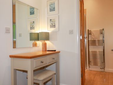 A small desk with a lamp and stool under a wall mirror next to a door leading to a bathroom with a towel rack at 14 Horizon View in Dobwalls