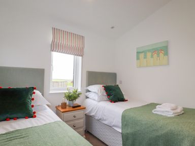 A bedroom with two single beds green pillows and blankets and a window with striped blinds at 14 Horizon View in Dobwalls