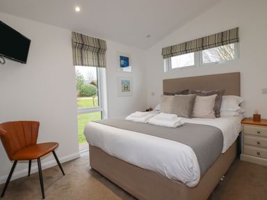 A bedroom with a bed with pillows and towels a chair a wall mounted television and windows at 14 Horizon View in Dobwalls