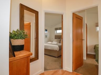 A hallway with wooden doors leading to two bedrooms and a wooden cabinet with a potted plant and a large mirror at 14 Horizon View in Dobwalls