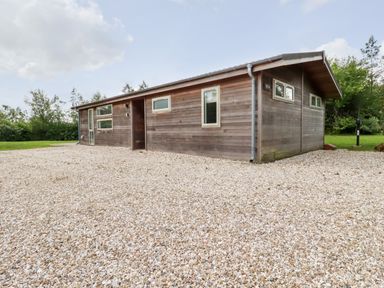 A wooden single-story house with multiple windows on a gravel driveway surrounded by greenery at 14 Horizon View in Dobwalls