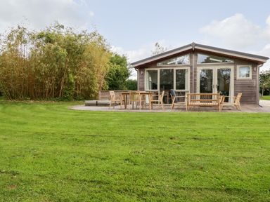 A wooden house with large windows and a deck with wooden outdoor furniture on a grassy lawn at 14 Horizon View Dobwalls