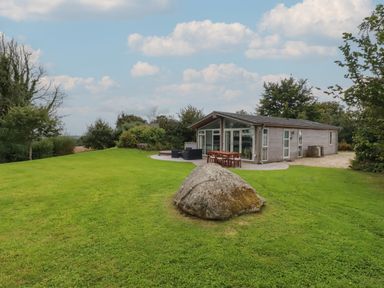 A house with outdoor furniture on a lawn with a large rock in front at 9 Horizon View in Dobwalls