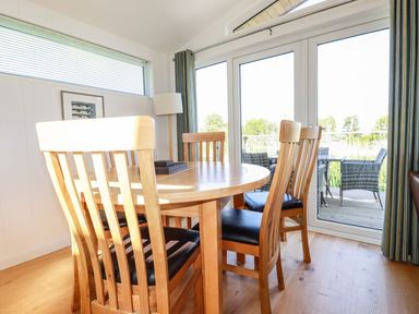 A dining area with a wooden table and chairs near glass doors opening to a balcony at 5 Meadow Retreat in Dobwalls